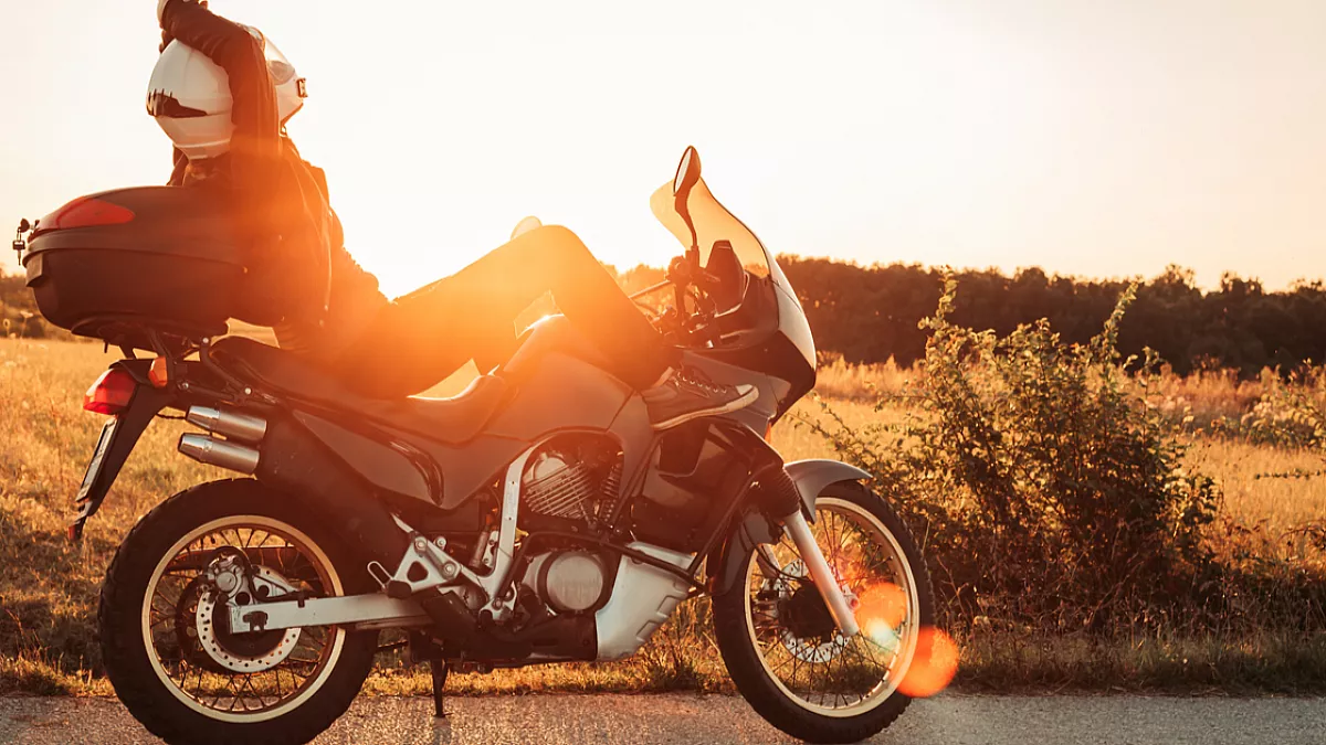 Pilota seduto sulla moto mentre osserva il tramonto