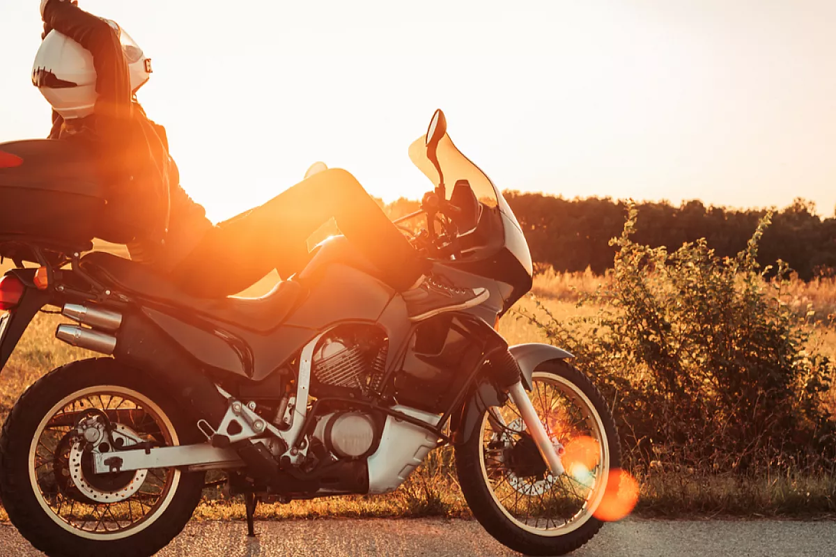 Pilota seduto sulla moto mentre osserva il tramonto