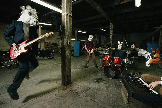 La band al completo in garage, con le moto sullo sfondo. Foto Timothy Saccenti