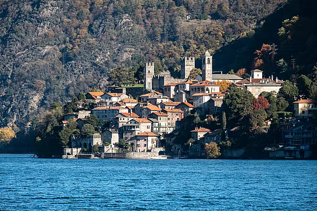 Uno sguardo su Corenno Plinio: in alto le torri del castello e il campanile della chiesa; in basso il molo. Invisibili da qui, i mille gradini che contraddistinguono il borgo. 